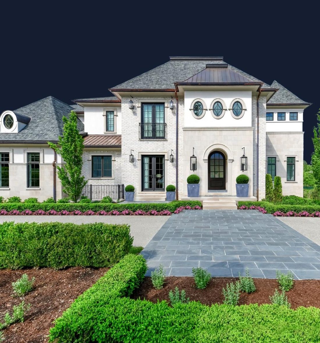 Luxury stone and stucco home with manicured front gardens